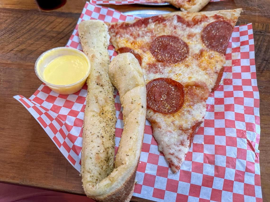 A slice of pepperoni pizza and a breadstick from Goodfellas Pizzeria
