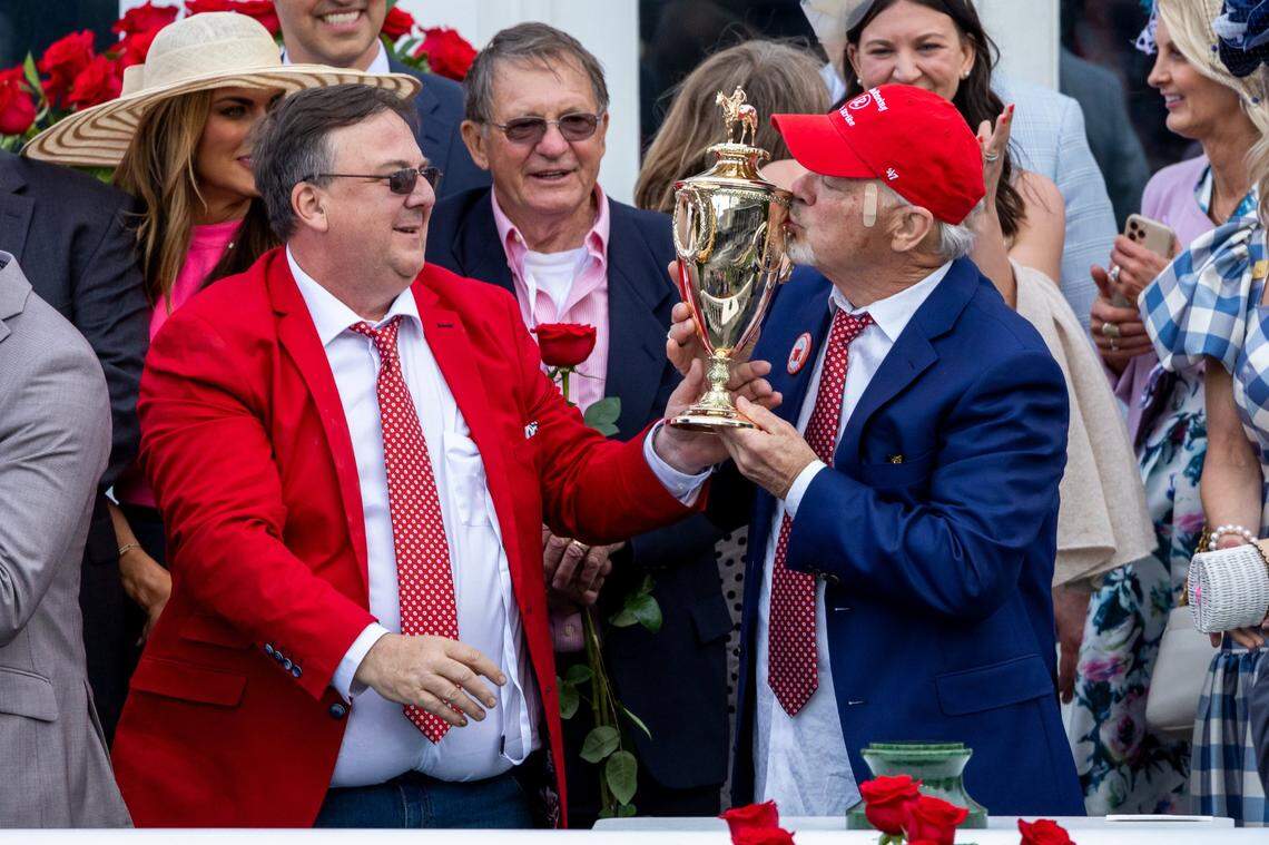 Richard Dawson, the owner of Kentucky Derby winner Rich Strike, kisses the trophy as trainer Eric Reed, left, watches during the celebration after Saturday’s race.