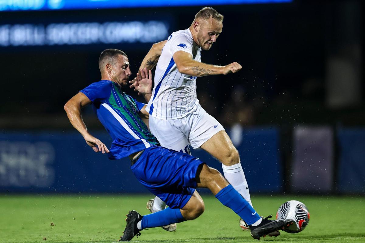 Kentucky midfielder Casper Grening, right, tries to elude a Florida Gulf Coast defender during Thursday night’s season opener in Lexington. Grening led the Wildcats last season with 11 goals.