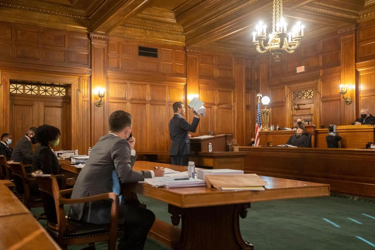 Chad Meredith, Kentucky solicitor general, holds up what he says is a stack of Kentucky Gov. Andy Beshear’s COVID-19 regulations as he arguments before the Kentucky Supreme Court as the state’s highest court hears arguments in the case that will decide whether Beshear’s emergency COVID-19 regulations, like wearing a mask, are constitutional at the Supreme Court chamber in the state Capitol in Frankfort, Ky., Thursday, Sept. 17, 2020.