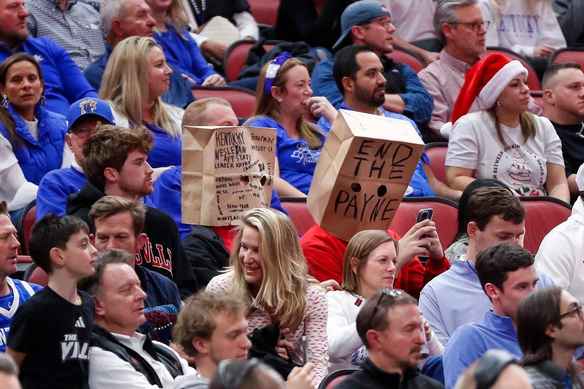 Fans wear paper bags with messages about Louisville Cardinals men’s basketball head coach Kenny Payne during Thursday’s game against the Kentucky Wildcats at the KFC Yum Center.