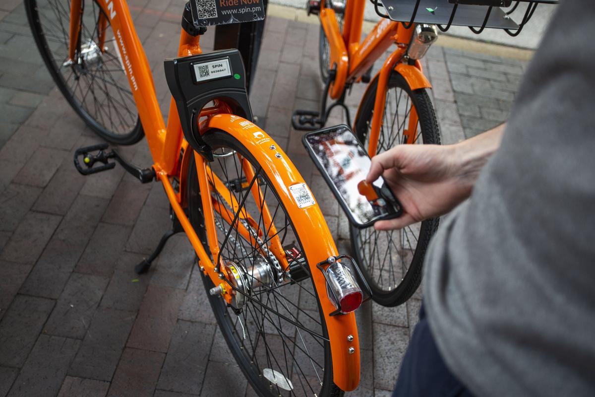 Michael Lewis scans the QR code on the back of a Spin bike with the Spin app in downtown Lexington. Each Spin bike is equipped with a GPS tracker that is powered by a solar panel.