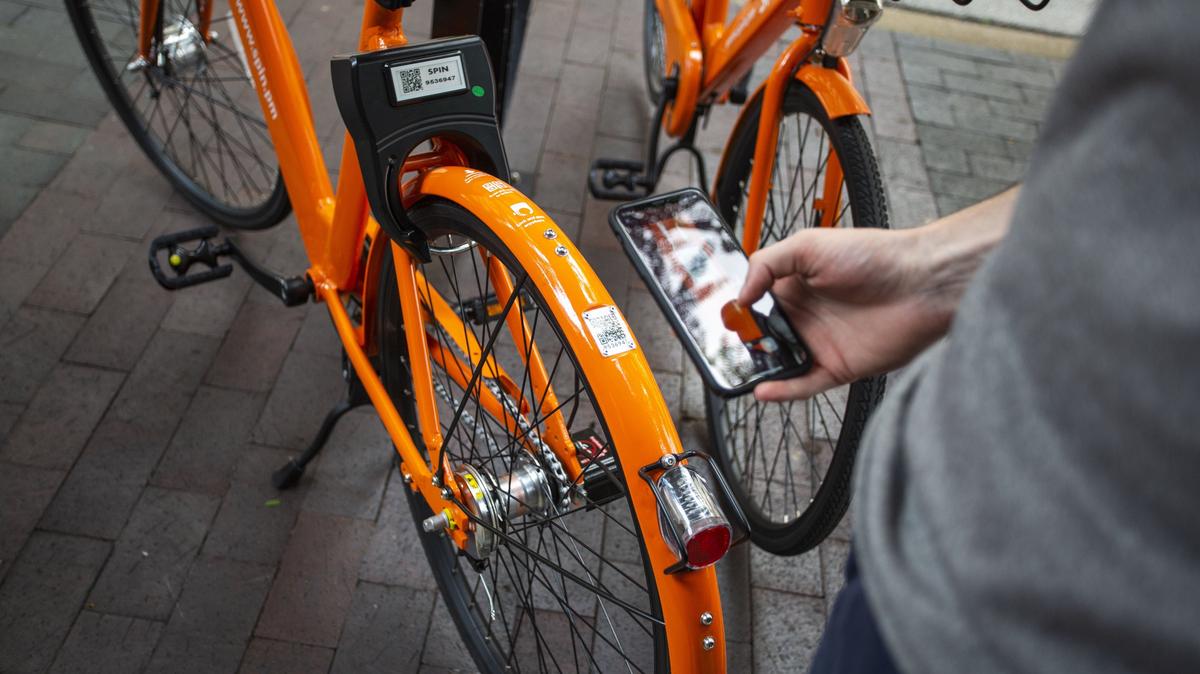 Michael Lewis scans the QR code on the back of a Spin bike with the Spin app in downtown Lexington. Each Spin bike is equipped with a GPS tracker that is powered by a solar panel.