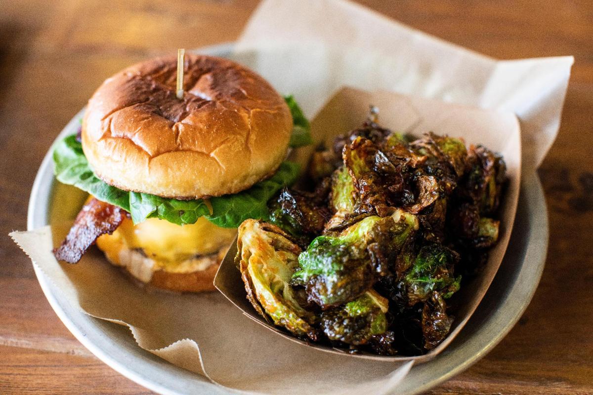 The Americano Burger and Brussels sprouts from the Wrigley Taproom in Corbin, Ky., Wednesday, June 16, 2021. The burger is made with Moonlight Farm beef, American cheese, lettuce, applewood bacon and garlic aioli.