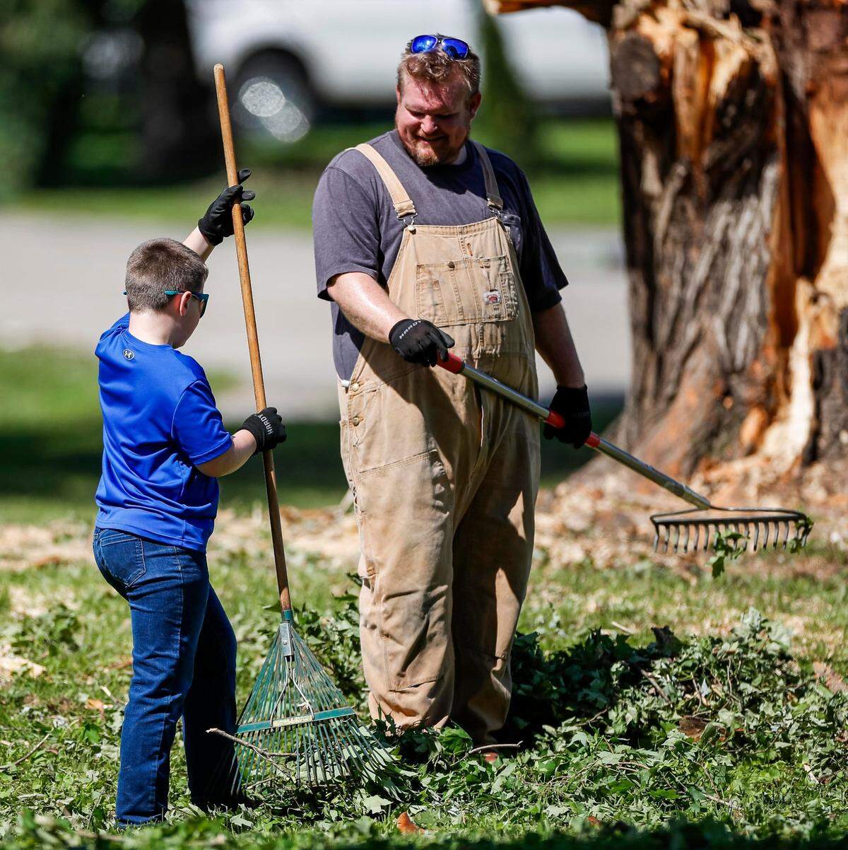 Chris Cook, right watches his son rake branches from a fallen tree on Sunday, May 18, 2025, at the Boedy house off U.S. Route 27 in Somerset, Ky. Cook said his sons wanted to be out helping, anyway they could.