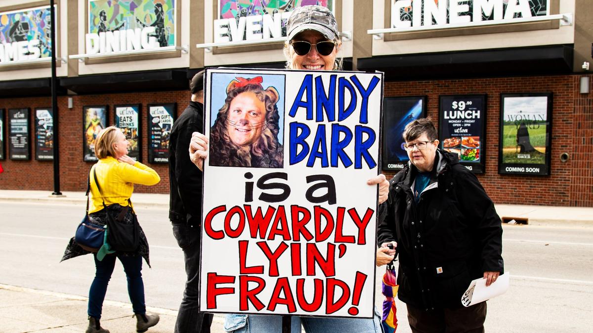 Alison Craig continues her protest of Rep. Andy Barr with a sign depicting him as the Cowardly Lion from the Wizard of Oz, referring to him as a “Lyin’ Fraud,” on March 19, 2025, during the Commerce Lexington policy luncheon at the Hyatt Regency in Lexington, Ky.