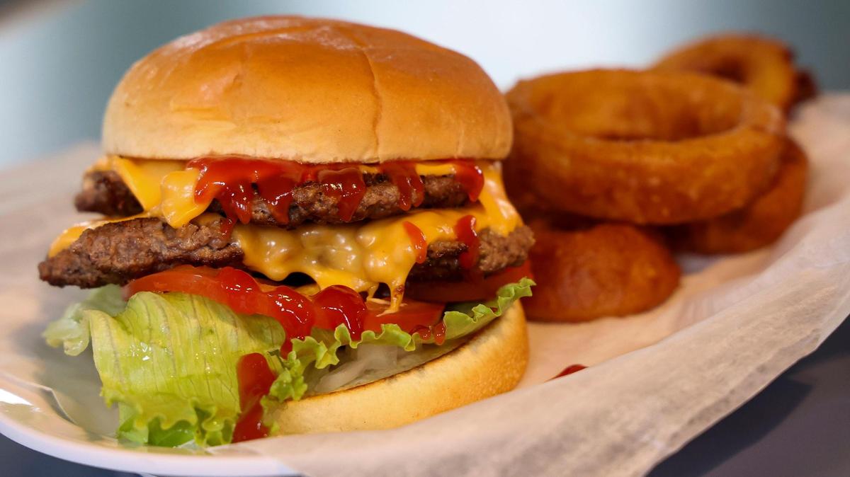 A Double Flame Burger ($7.25) with American cheese, lettuce, tomato, onions and ketchup and a side of onion rings at JJ burgers and fries, Thursday, Nov. 23, 2024 in Lexington, Ky. The new restaurant is located in the unincorporated community of Athens in southern Fayette County.