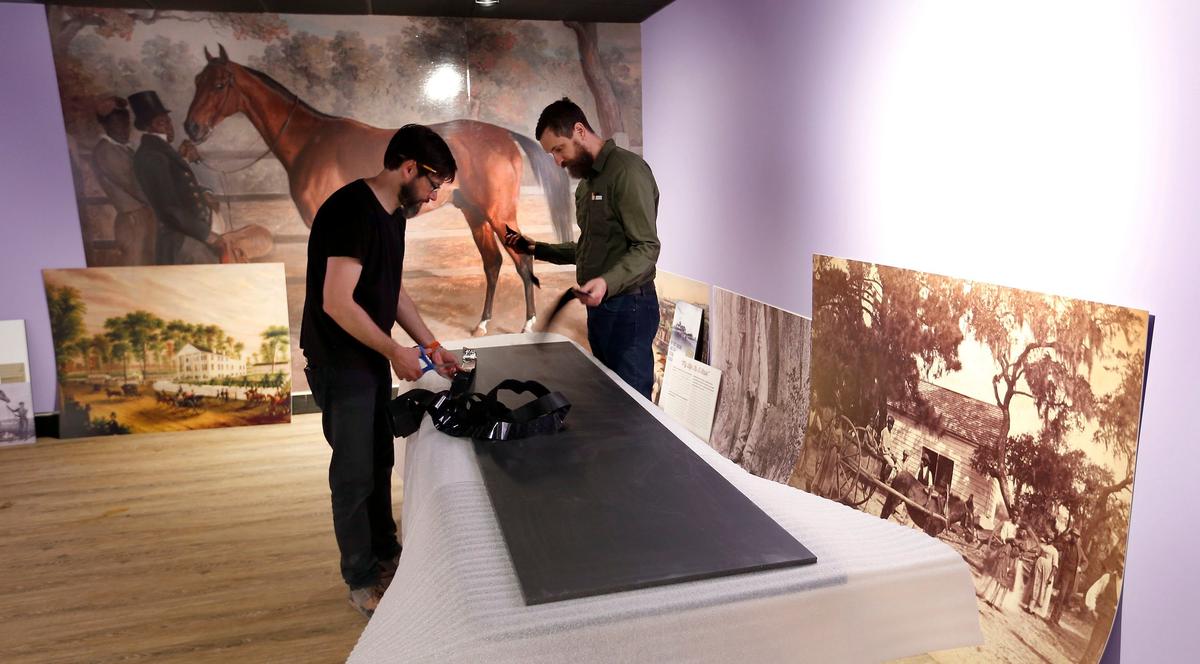 James Shambhu. left, and Travis Robinson, right, worked on installing the Black Horsemen of the Turf exhibit located in the International Museum of the Horse at the Kentucky Horse Park on Iron Works Road. This exhibit was the last exhibit done by museum director Bill Cooke before he retired. The large painting in the background is a painting of Richard Singleton being held by black horseman Harry Lewis painted by equine artist Edward Troy.