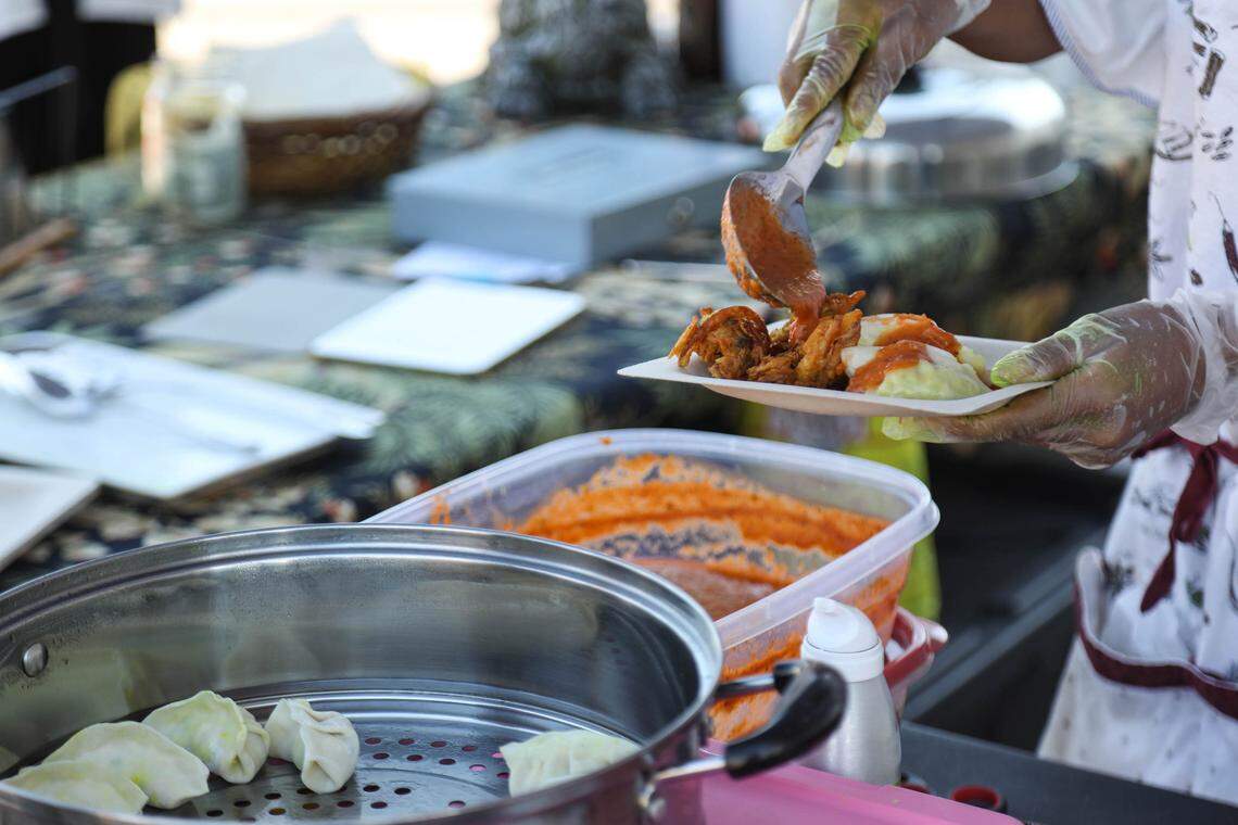 Shrestha pours spicy tomato achar onto dumplings and pakora, a vegetable fritter.