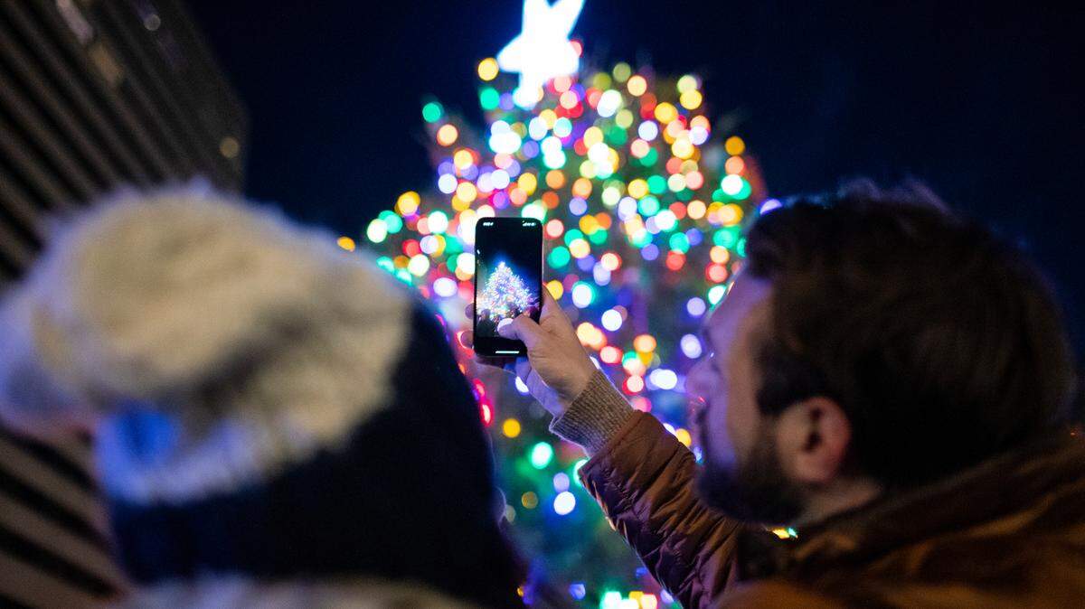 People take photos after the Christmas tree was light during the Holiday Lighting Festival at Triangle Park in Lexington, Ky., Sunday, November 28, 2021. The festival included a Òletters to SantaÓ station, take-home craft, vendor booths and ice skating.