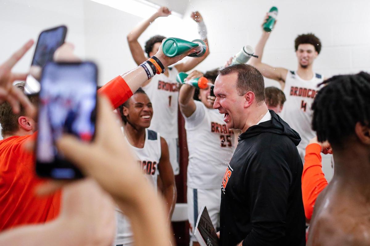 Frederick Douglass head coach Wes Scarberry is sprayed with water while entering the locker room after winning the 11th Region Tournament in Richmond last week.