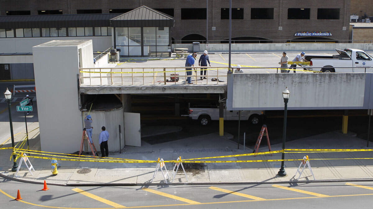 City employees put up a temporary wooden guard rail while co-workers inspected and worked Monday on the Phoenix parking garage. A 28-foot concrete panel fell from the Vine Street structure Sunday.