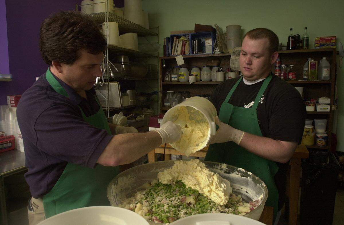 Stanley J. Tarnofsky and Jerald Lemaster put the last ingredients, mayonnaise and sour cream, into a batch of secret recipe potato salad at Stanley J.’s New York Style Delicatessen