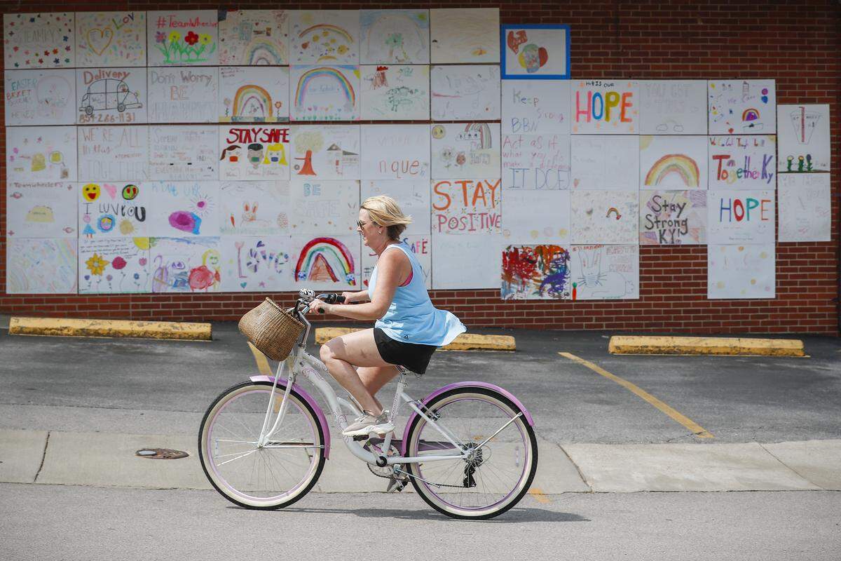A cyclist passes dozens of hand drawn inspirational posters on display Wednesday at Wheeler Pharmacy.