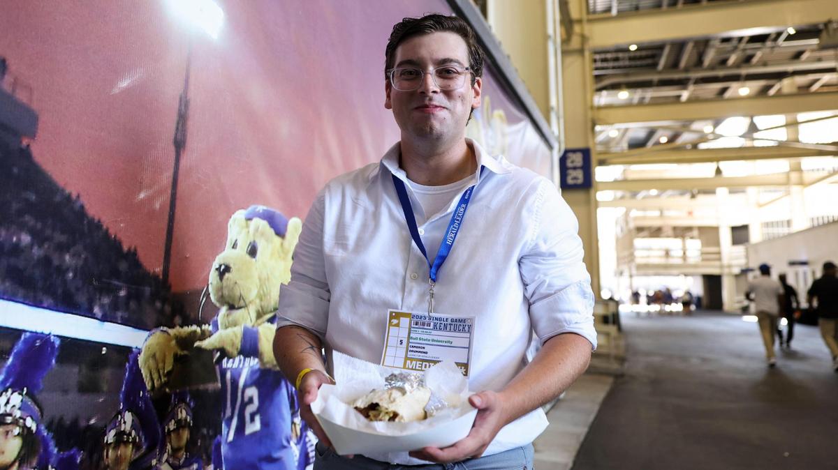 Lexington Herald-Leader reporter Cameron Drummond poses with his steak burrito purchased from Nathan’s Taqueria before Kentucky’s home football game against Ball State. Drummond sampled food from a variety of Kroger Field concession stands before and during the game.