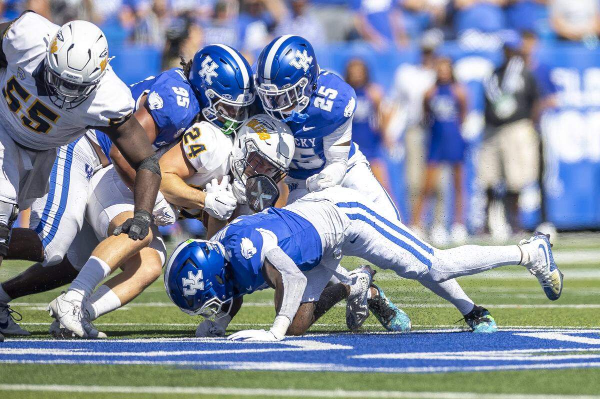 Kentucky defensive lineman Jerod Smith (95) and defensive back Jordan Lovett (25) wrap up Toledo running back Connor Walendzak (24) during Saturday’s game at Kroger Field.