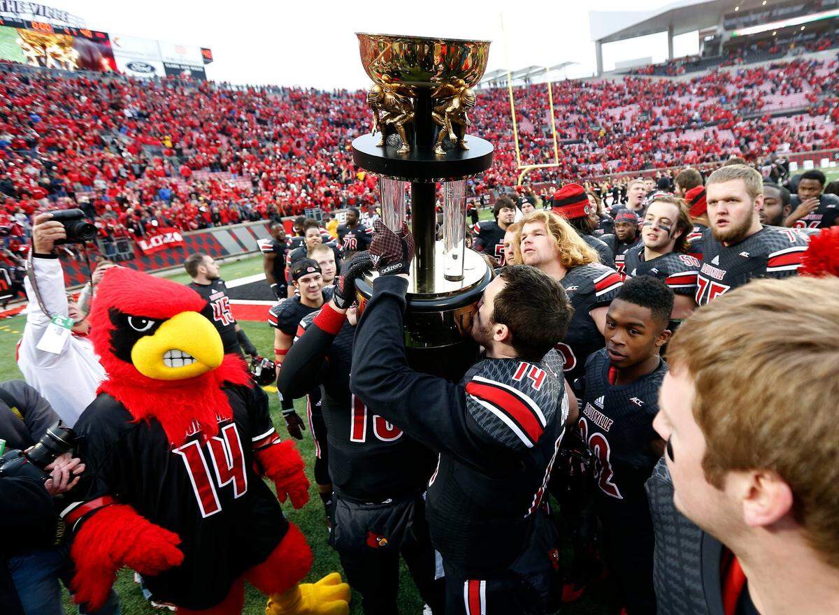 Louisville quarterback Kyle Bolin (14), who played at Lexington Catholic High School, kissed the Governor’s Cup trophy after rallying U of L to a 44-40 come-from-behind victory over Kentucky in 2014.