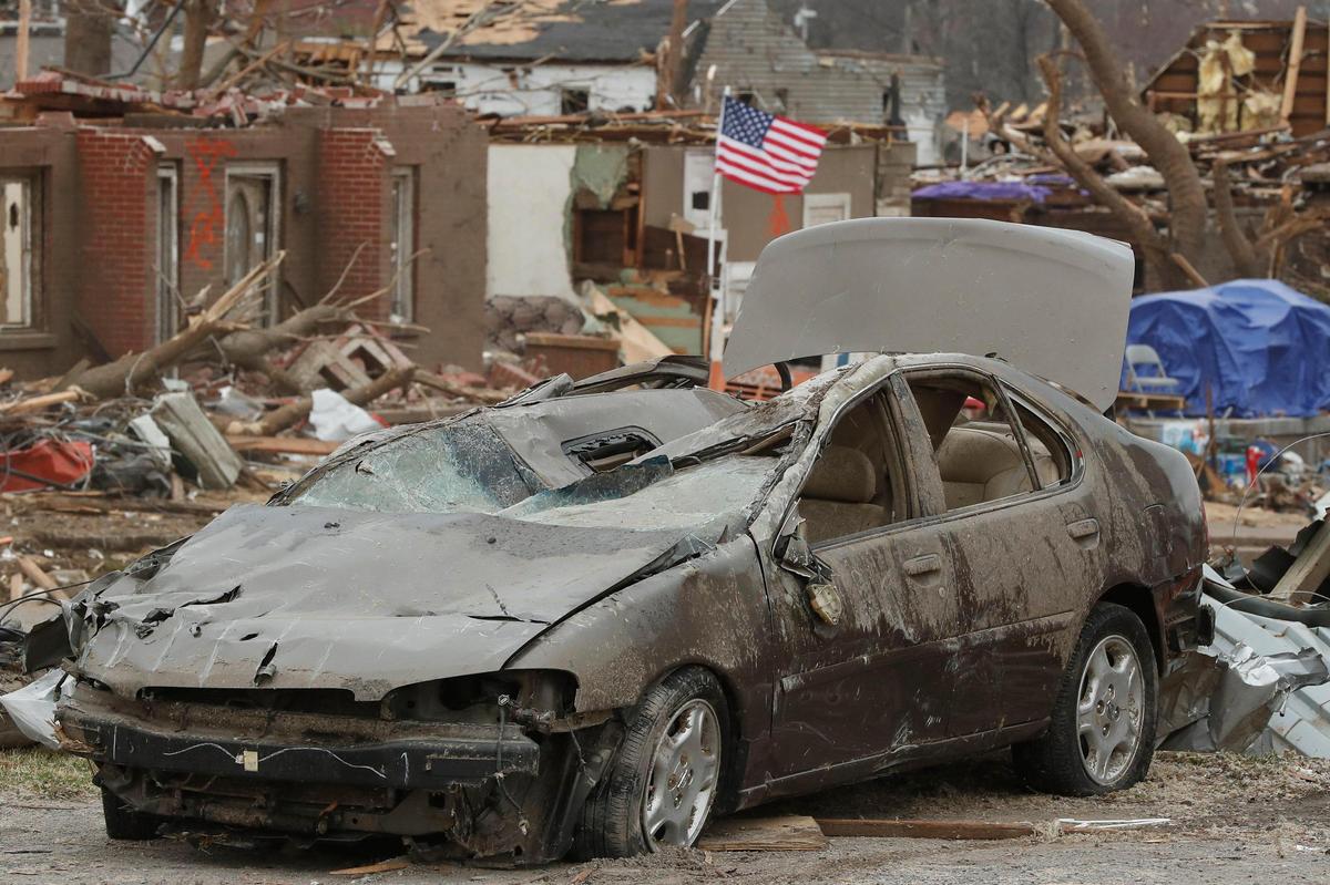 A wrecked Nissan sedan sits among destroyed houses and other debris along North 6th Street in Mayfield, Ky.