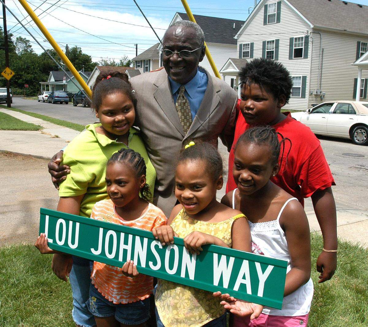 Lou Johnson, holding his copy of a Lexington street sign named in his honor, had his photo taken with local children after the ceremony dedicating Lou Johnson Way in 2004.