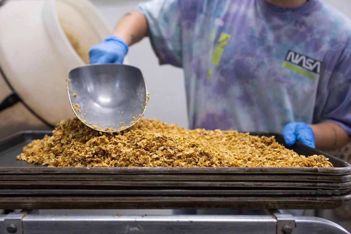 Team member MB Mercer flattens granola before it moves onto the next steps of preparing it on Thursday, July 25, 2024, at Sweetgrass Granola in Lexington, Kentucky.