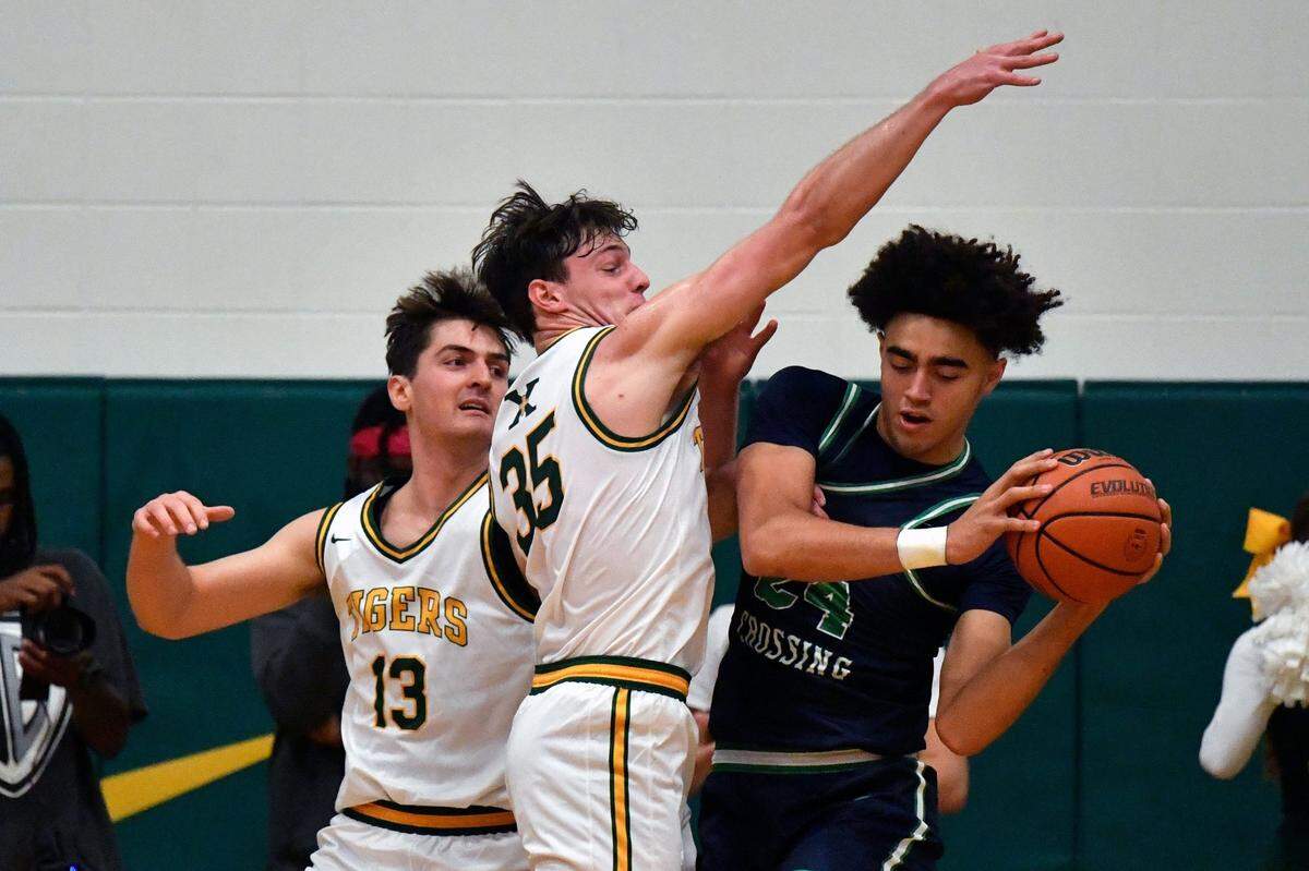 St. Xavier's Will Hanke (35) and Graham Krezmien attempt to get the ball away from Great Crossing's Malachi Moreno (24) during the first half of their high school basketball game, Sunday, Dec. 15 2024 in Louisville Ky.