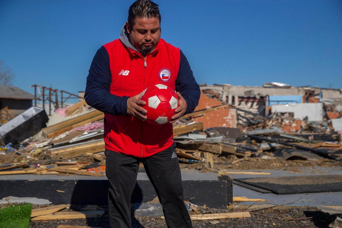 Luis ‘Chili’ Pardo’s picks up a soccer ball from the debris of the former Pardo’s ‘Soccer Factory,’ an indoor facility he owns, in Mayfield, Ky., on Monday, Dec. 13, 2021.