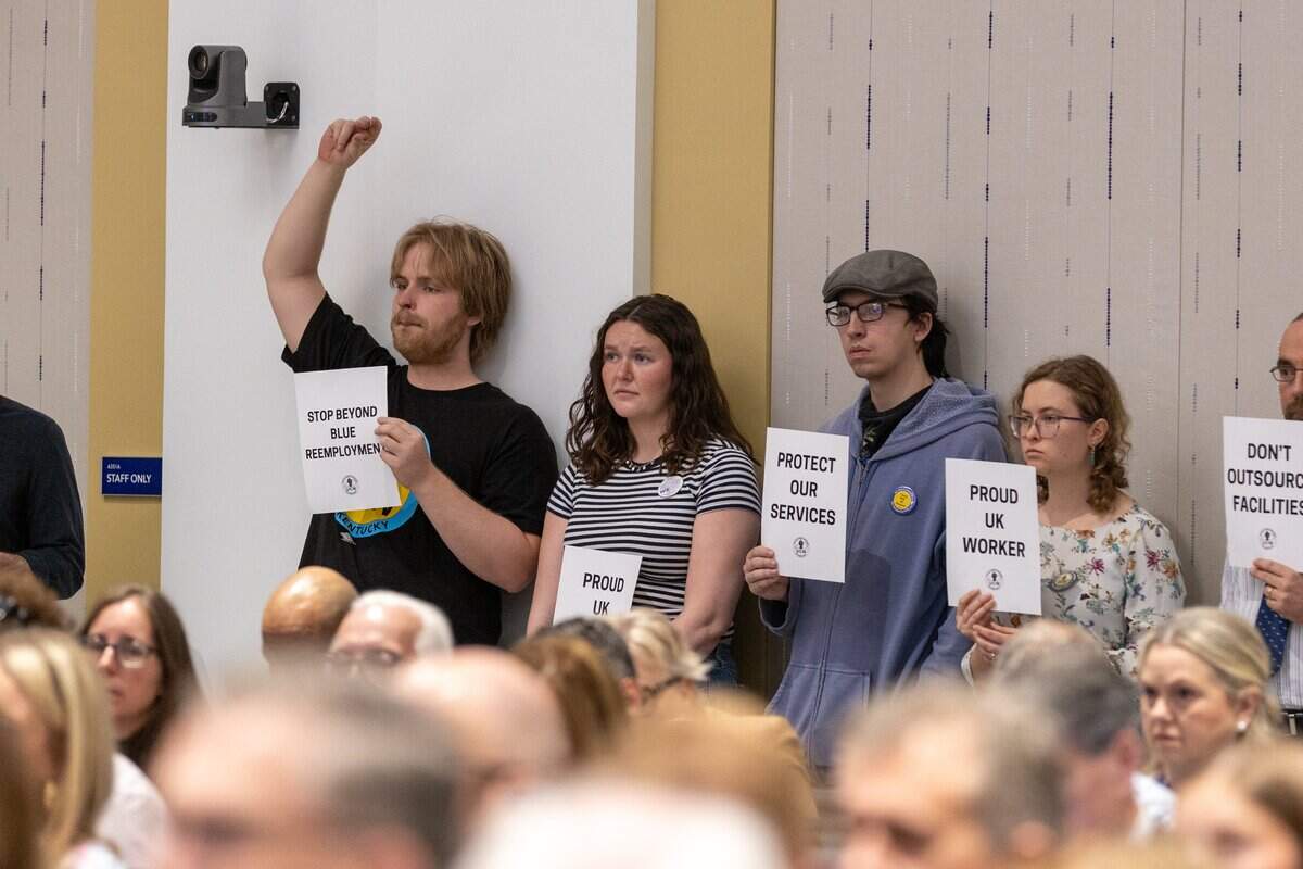 UK graduate student Eli Wrinn, left, gently snaps his fingers in the air in a reaction to a UK board of trustees member speaking during a meeting Friday morning. He is joined with several other students and faculty, including members of United Campus Workers of Kentucky, in protest of the appointment of federal judge Gregory Van Tatenhove to the dean position at College of Law during a board of trustees meeting in the Gatton Student Center. April 24, 2026.