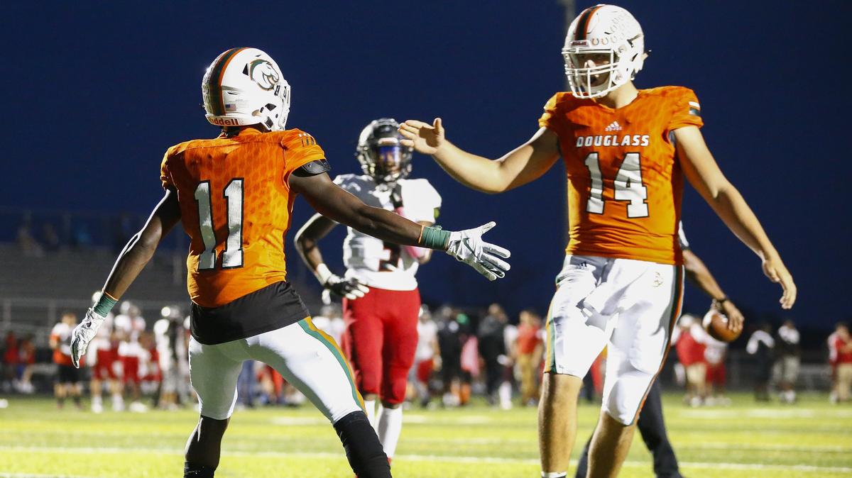 Frederick Douglass’ Dekel Crowdus (11) celebrated a touchdown with quarterback Cameron Jones (14) as Dunbar’s Dre Thruston (3) looked on during their game Friday at Frederick Douglass High School in Lexington. Frederick Douglass won 49-15.
