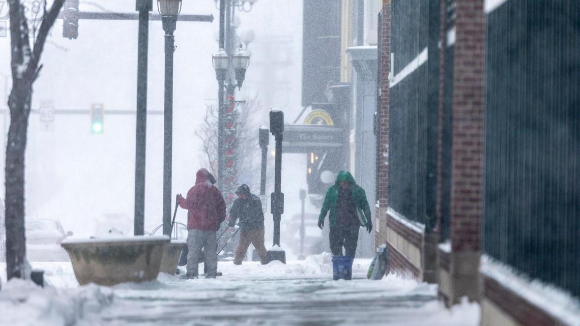 People clear snow from a sidewalk in downtown Lexington, Ky., Sunday, Jan. 5, 2025.