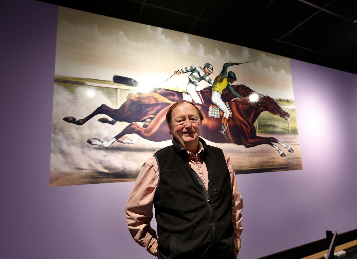 Bill Cooke stood in front of a painting of Isaac Murphy riding Salvator in a New York race called the Suburban  which is part of the Black Horsemen of the Turf exhibit located in the International Museum of the Horse at the Kentucky Horse Park on Iron Works Road. This exhibit was the last exhibit done by museum director Bill Cooke before he retired.