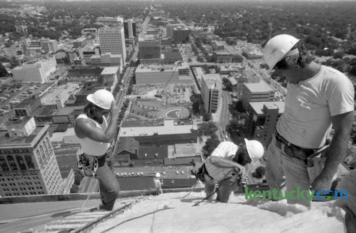 Danny Rhymer, left and Michael Stanford, right, watch Junior Jones attach a piece of roofing onto the Lexington Financial Center June 19, 1986. The men worked for W.F Martin Company and were installing sheet metal roofing on the nearly complete building in downtown Lexington. At the center of the photo is what is now Phoenix Park and the site of the Lexington Public Library building. The Lexington Financial Center, know as “Fifth Third” or the “Big Blue Building”, is a 410 foot 31 floor high-rise and was completed in 1987. It’s the tallest building in Kentucky outside Louisville. Photo by Ron Garrison | Staff