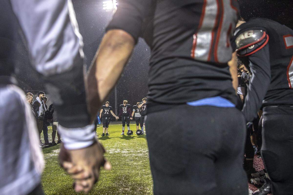 Harlan County players and coaches hold hands after beating Perry County.