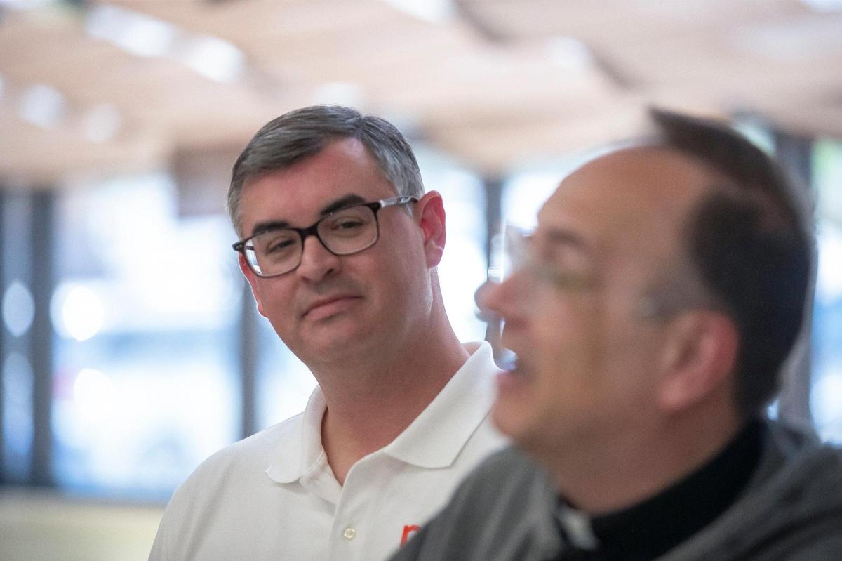 Greg Ferrara, president of the National Grocers’ Association, listens as Father Jim Sichko — the Papal Missionary of Mercy from Lexington — explains why he’s giving a case containing $75,000 to Gwen and Arthur Christon to help reopen the Isom IGA grocery store they own on Wednesday, Aug. 31, 2022. The grocery store was devastated by flood waters in July.