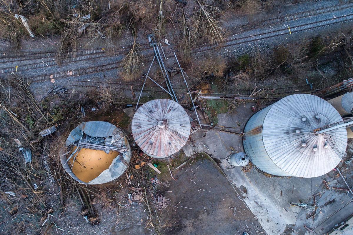 Silos next to railroad tracks on the edge of downtown Mayfield, Ky., are heavily damaged Sunday, Dec. 12, 2021 as downed trees litter the ground.