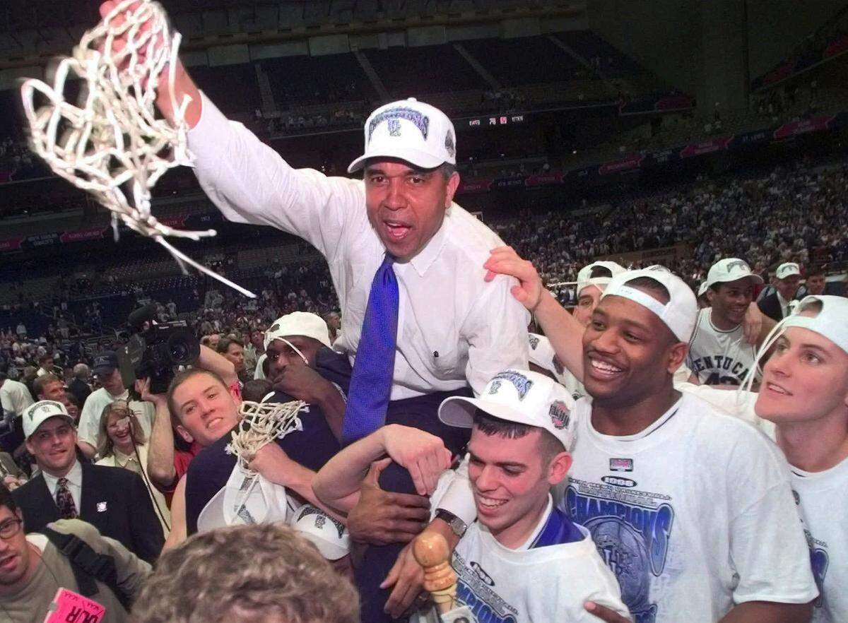 ** FILE ** Kentucky Coach Tubby Smith is carried off the court by game MVP Jeff Sheppard, left, Steve Masiello, center right, and Jamaal Maglioire second from right front at the Alamodome in San Antonio Monday, March 30, 1998. Other players, cheerleaders and fans surround. This was Kentucky’s seventh NCAA tittle. The Wildcats are celebrating 100 years of basketball this season. The span has been defined by an unprecedented 1,834 victories and 43 NCAA tournament appearances. (AP Photo/Eric Draper)