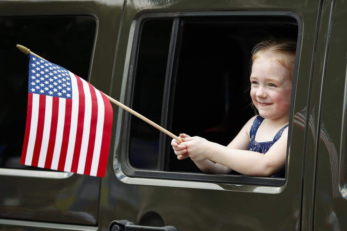 Katha Horseman, 4, of Lexington, Ky., waves an American flag from a VFW Post 680 jeep during the city of Lexington’s Fourth of July parade along Main Street in downtown Lexington Ky., Thursday, July 4, 2019.