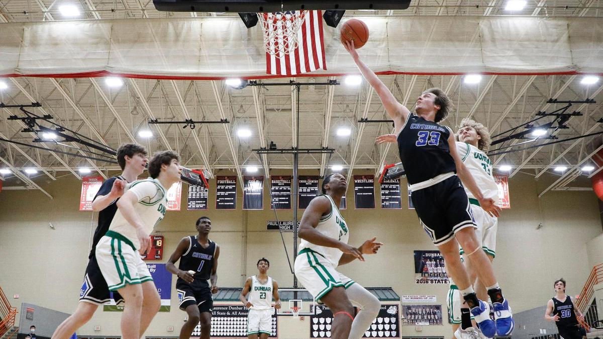Lexington Catholic’s Ben Johnson (33) shoots past Paul Laurence Dunbar’s Lionel Kumwimba (55) and Max VanDyke (31) during their game at Paul Laurence Dunbar High School In Lexington, Ky., Thursday, Feb. 25, 2021. Lexington Catholic beat Paul Laurence Dunbar 69-67.