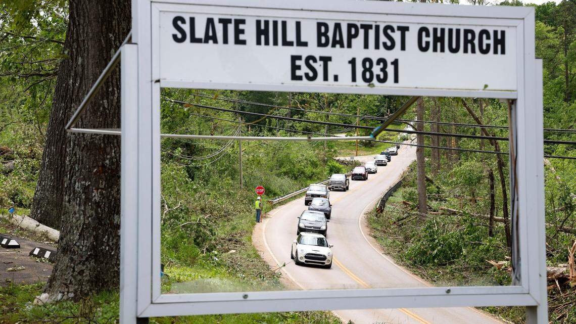 Part of the sign for Slate Hill Baptist Church is blown out as traffic on Barbourville Road was down to one lane in front of the church just outside of London, Ky. in Laurel County Sunday, May 18, 2025 as utility workers made repairs from down lines on the road. Two days earlier, thunderstorms and a deadly tornado ripped through the Southern Kentucky community destroying many homes.