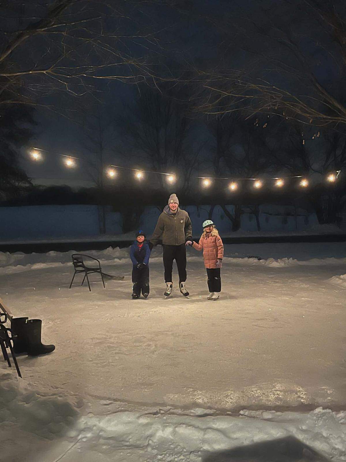 Jordan Hall (middle) poses for a photo with his 6-year-old son and 8-year-old daughter on the homemade ice rink he created in his front yard.