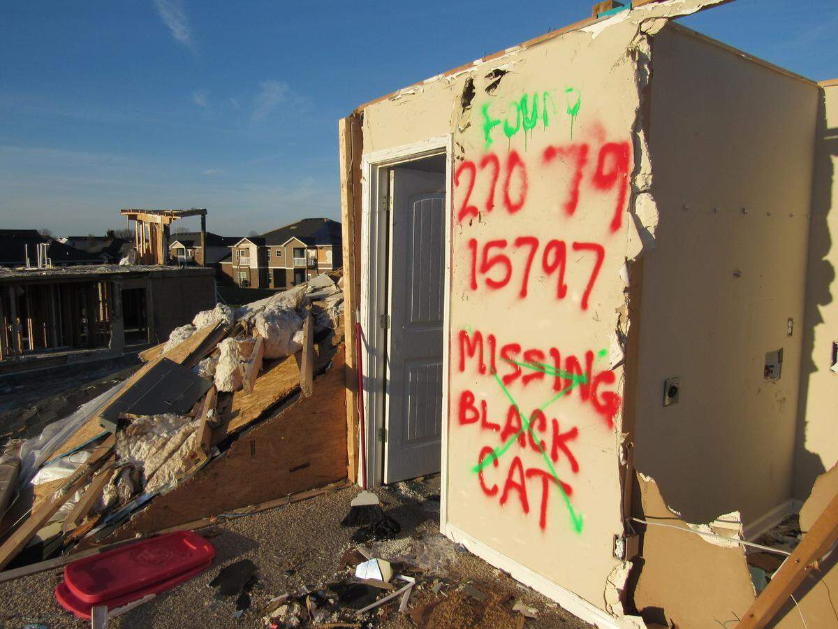 The former occupant of an apartment destroyed in a Dec. 11, 2021 tornado in Bowling Green, Ky., painted a sign on a section of drywall on the second floor in hopes of finding a pet lost in the storm.