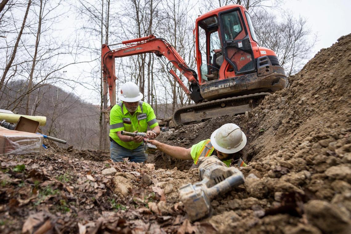 Dillon Fluegge and Brenden Wilkens work to repair a water main along a road outside Inez in Martin County, Ky., in this March 17, 2021, photo.
