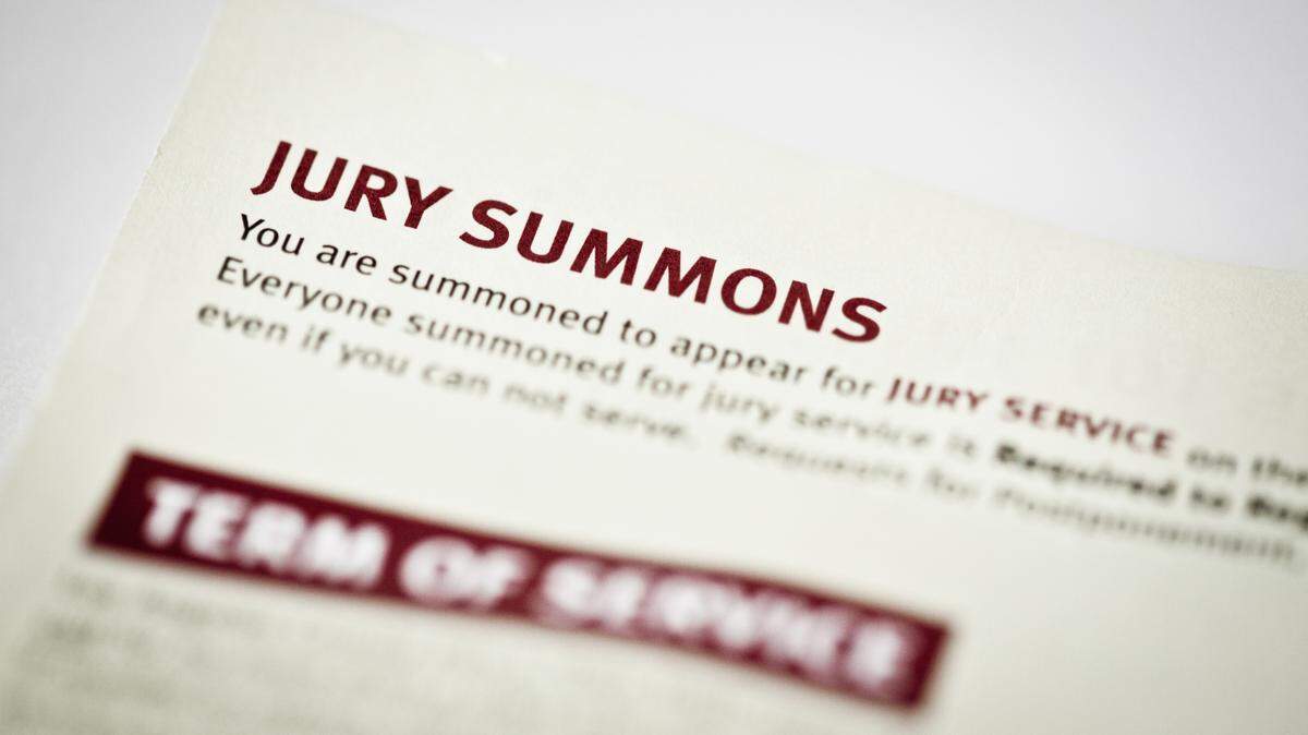 An image shows an up close view of a jury duty summons. There's a depth-of-field effect where the focus of the paper - "Jury Summons" - is in sharp focus, while the rest of the text on the page is blurred. 