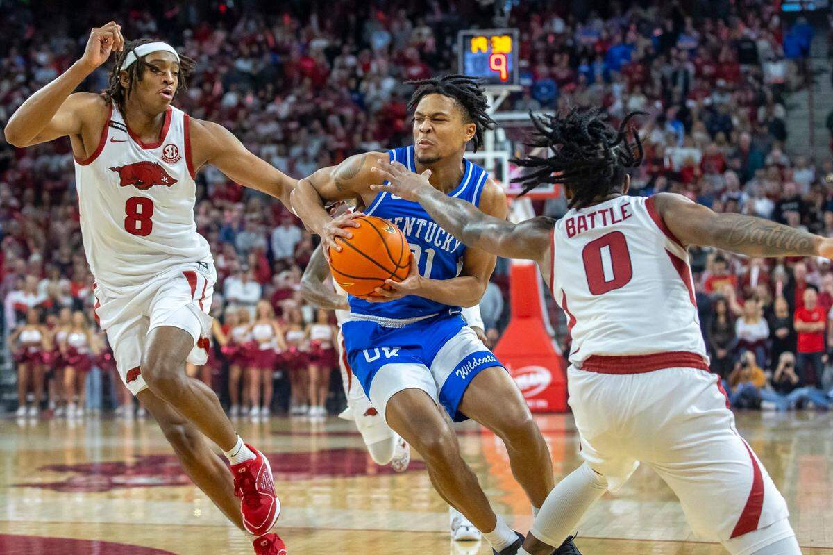 Kentucky’s D.J. Wagner (21) drives between Arkansas’ Chandler Lawson (8) and Khalif Battle (0) at Bud Walton Arena on Saturday night. Wagner finished with eight points and three assists.