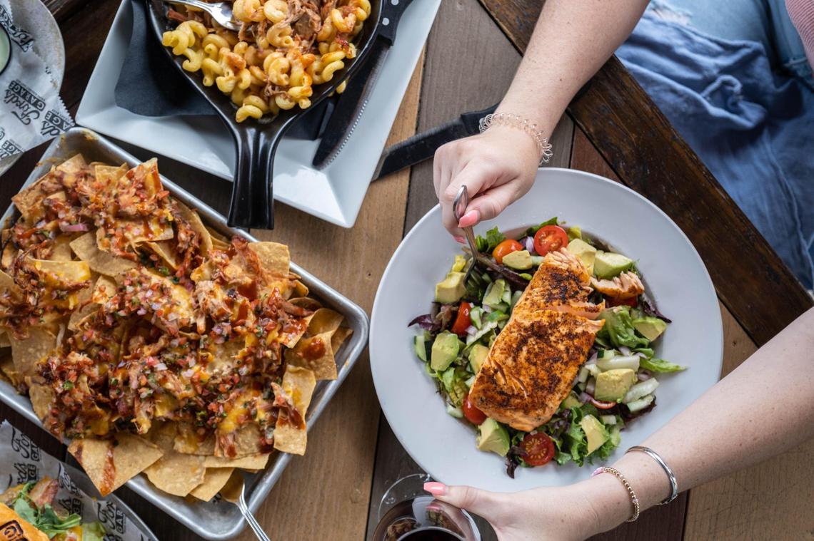 Though Ford’s Garage is mainly known for burgers, the menu also features appetizers, salads and comfort food. Shown here, clockwise from left, Ford’s Original Nachos ($14.99), Pulled Pork Mac N’ Cheese ($14.99) and Blackened Salmon Salad ($18.99).