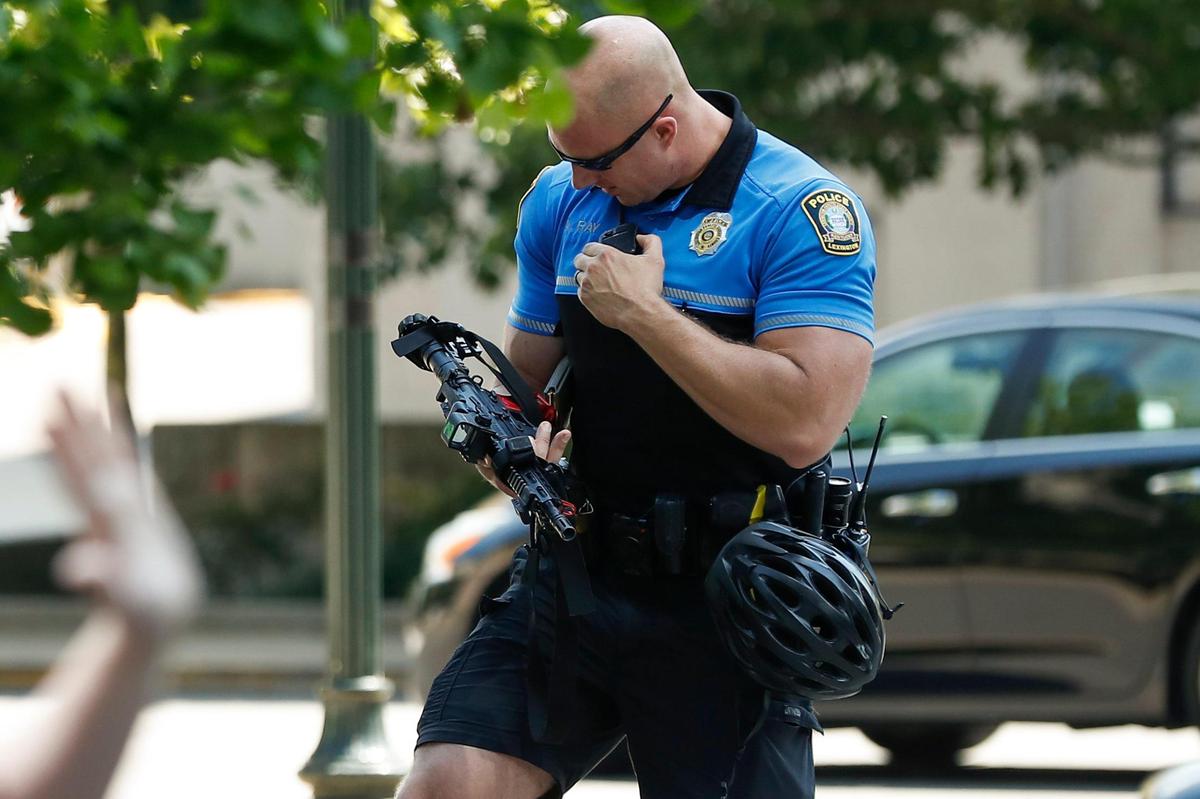 A Lexington police officer examines a semi-automatic firearm which demonstrators say was pointed at them by an occupant of an SUV who was sitting in blocked traffic along West Main Street during a protest against celebrating the Fourth of July through downtown Lexington, Ky., Saturday, July 4, 2020.