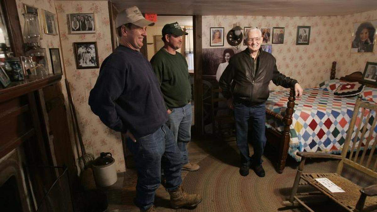 Herman Webb, right, Loretta Lynn’s brother, gave a tour and told a story to Raymond Sweet, left, and Johnny Carpenter in the interior of the house in Butcher Hollow where they grew up in Van Lear on Feb. 14,  2005.