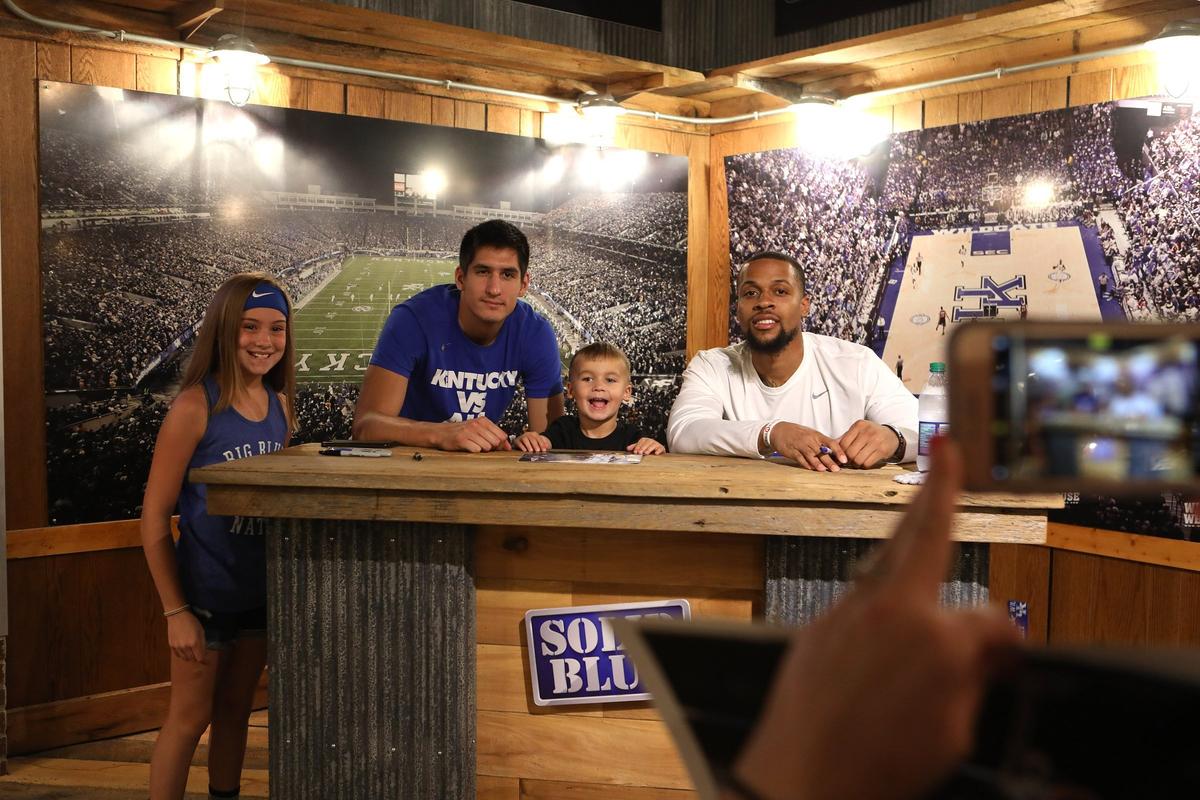 Kylie Earlywine, 10, and brother Griffin, 4, of Carlisle posed with former UK players Derek Willis and Isaiah Briscoe Tuesday at Wildcat Wearhouse. Photo by Matt Goins
