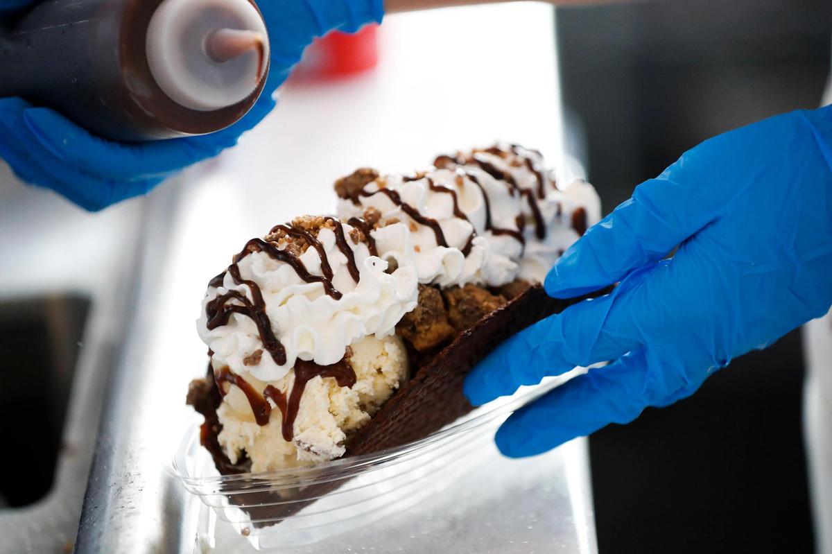 An ice cream taco featuring two scoops of cookies n’ cream, one scoop of butter pecan and topped with peanut butter cups, whipped cream and hot fudge served in a waffle cone at Hoggy’s Ice Cream in Frankfort.