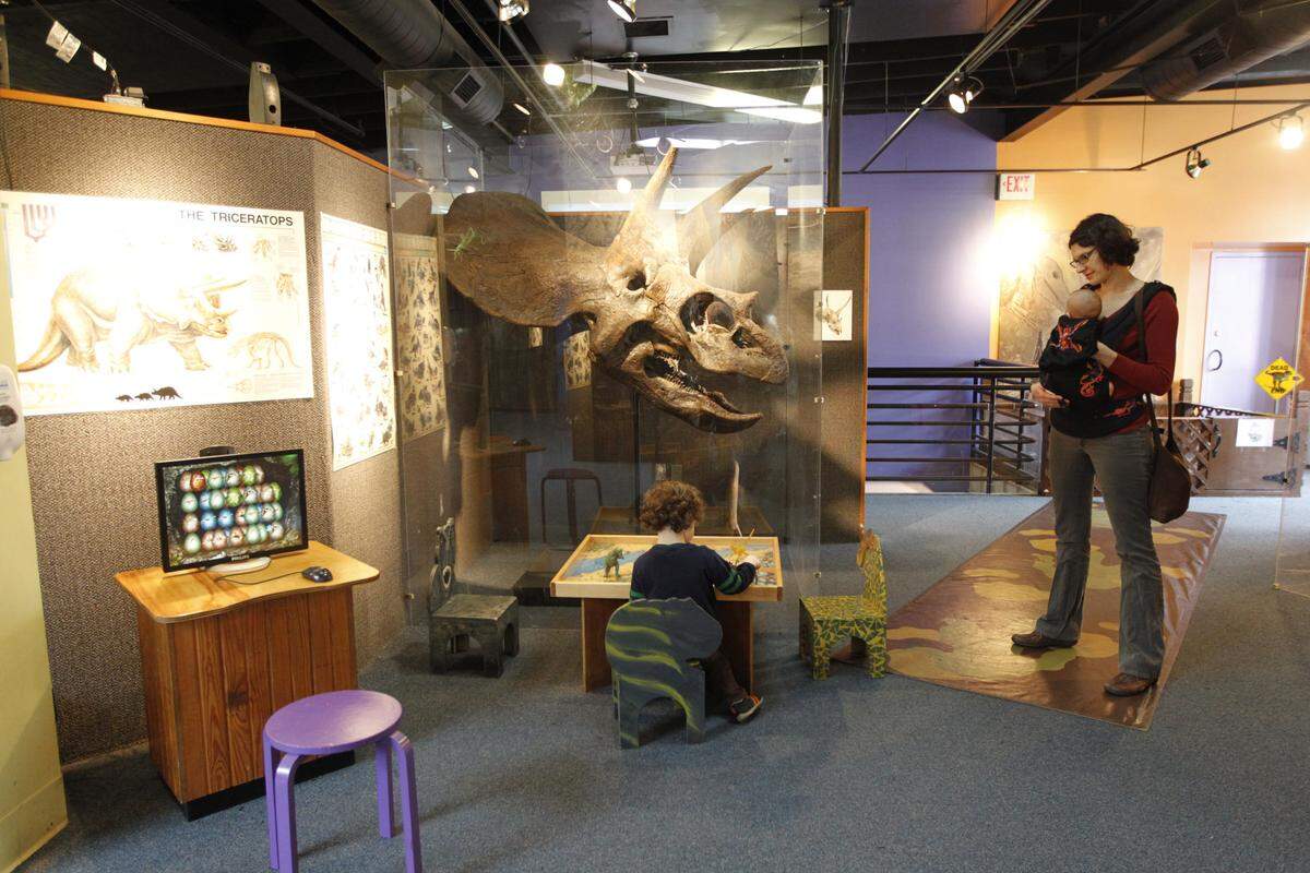 Eli Hays Lucas, 3, checked out the dinosaur area in the Explorium with his mother, Jessica Hays Lucas, and little brother Jonah. Photo by Pablo Alcala | Staff