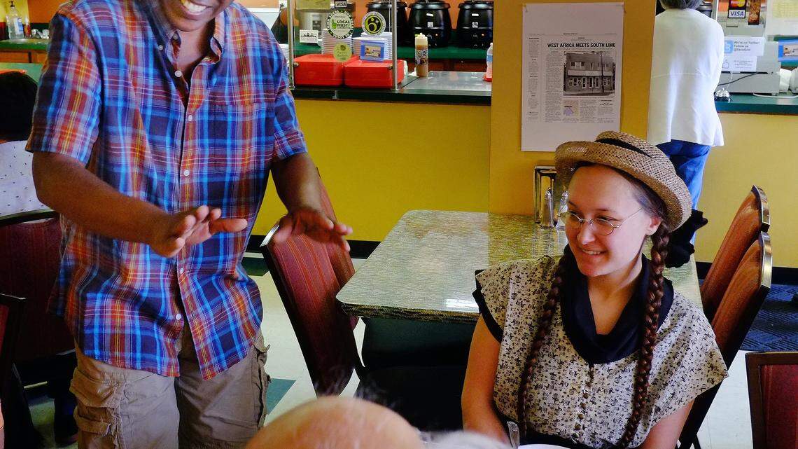 Mamadou "Sav" Savané, left, talked with regular customer Ron Pen, a University of Kentucky music professor, and Erin Fulton last Wednesday. Savané returned to work for a few hours each day last week as he continued his recovery from a June 3 kitchen accident that left him badly burned.